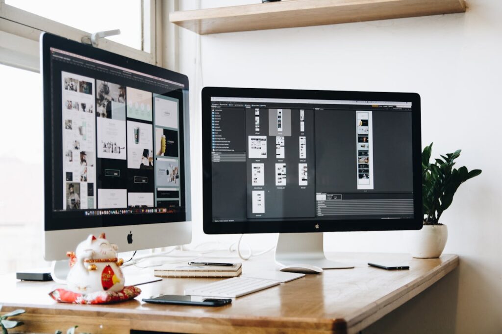 Stylish office workspace featuring dual monitors, a keyboard, notebooks, and decorative plant.